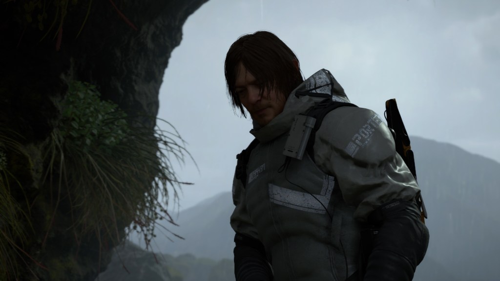 A screenshot from Death Stranding where the main character wearing wet, plated armor is looking down and entering a green, mossy area